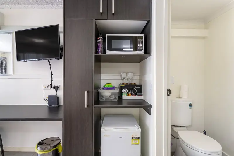 Kitchenette shelving with a kettle, cups and a microwave